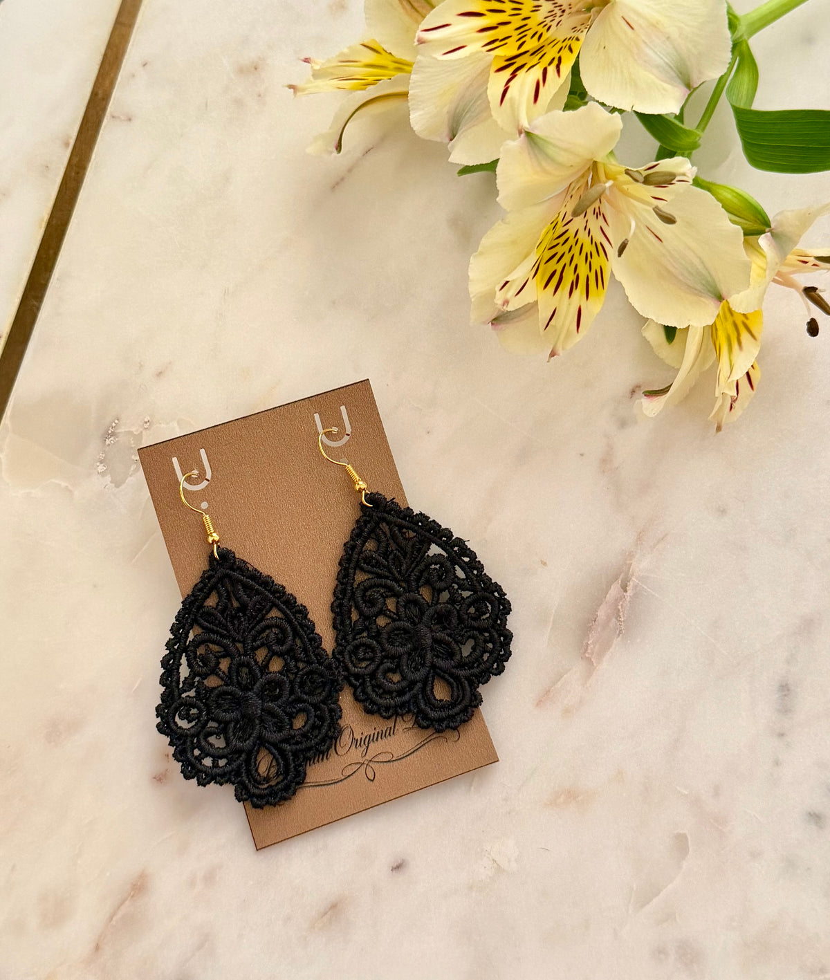 White and gold teardrop earrings made from embroidery on display card